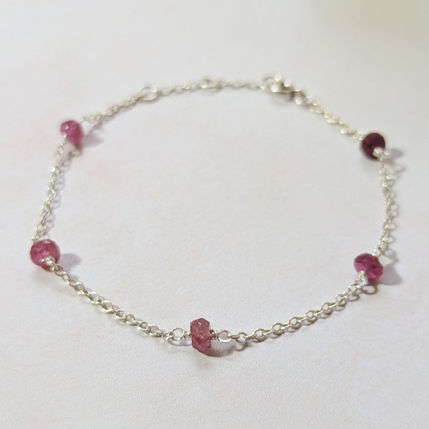 Silver station bracelet with Ruby gemstone beads on a white background.