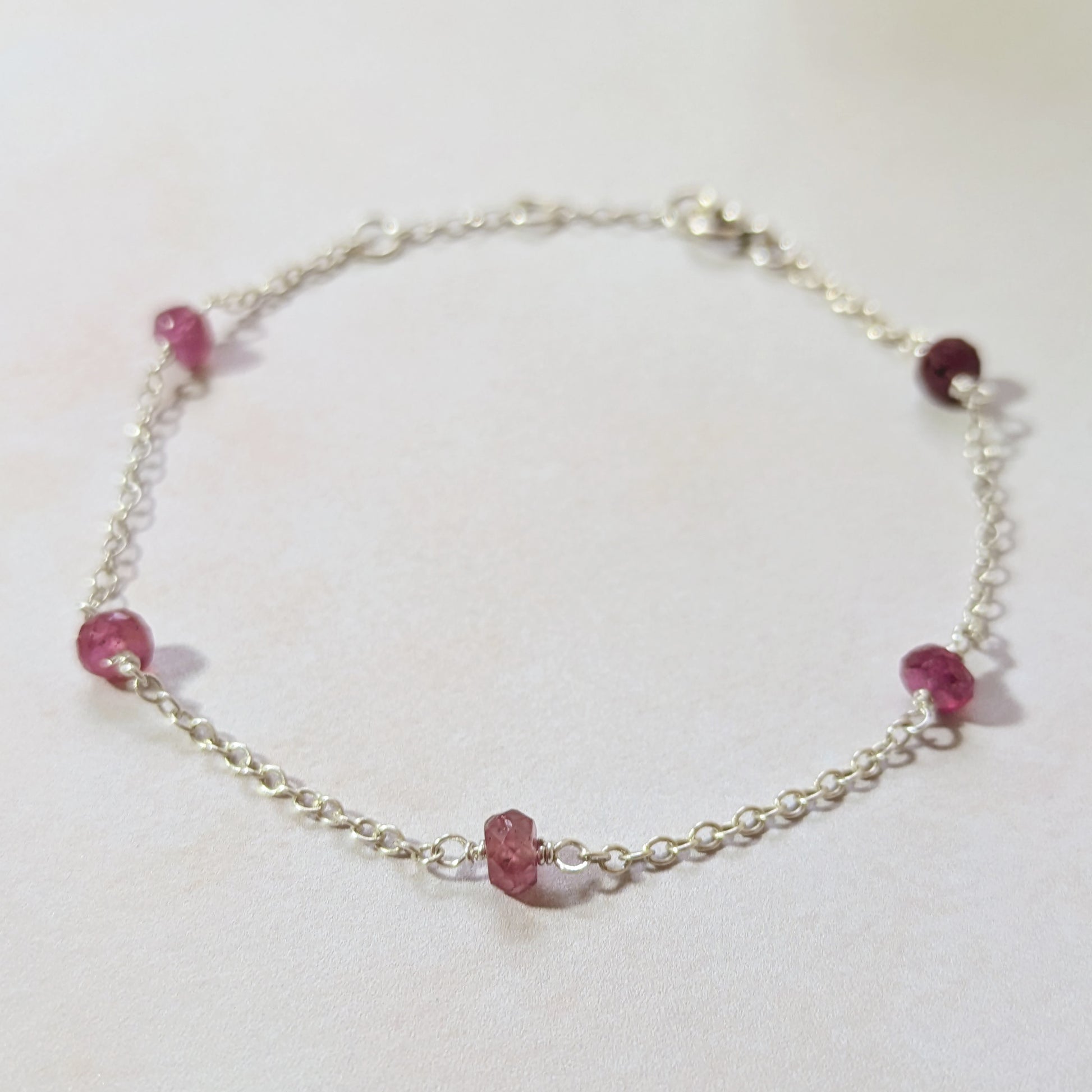 Silver station bracelet with Ruby gemstone beads on a white background.