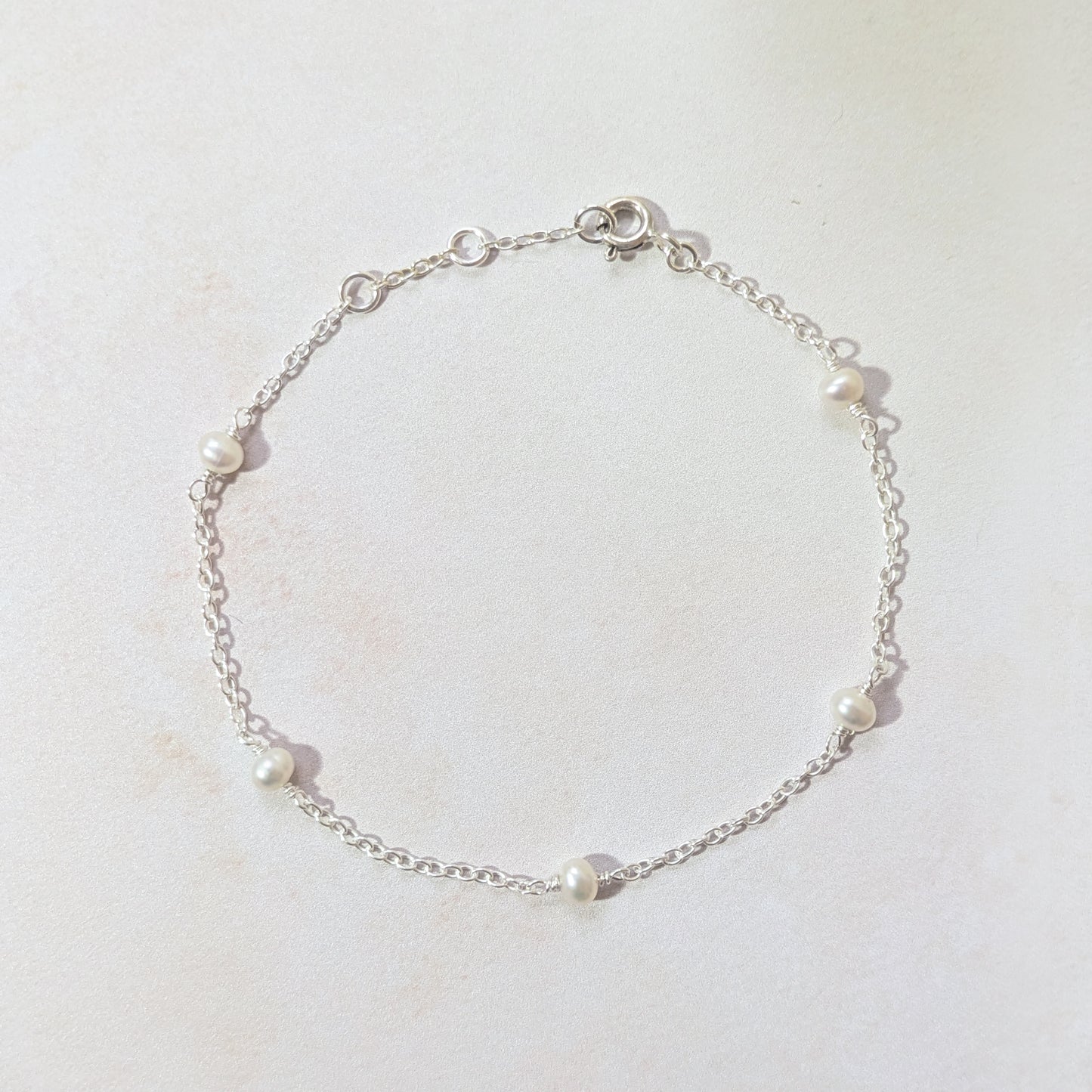 Silver bracelet with pearls on a light background.