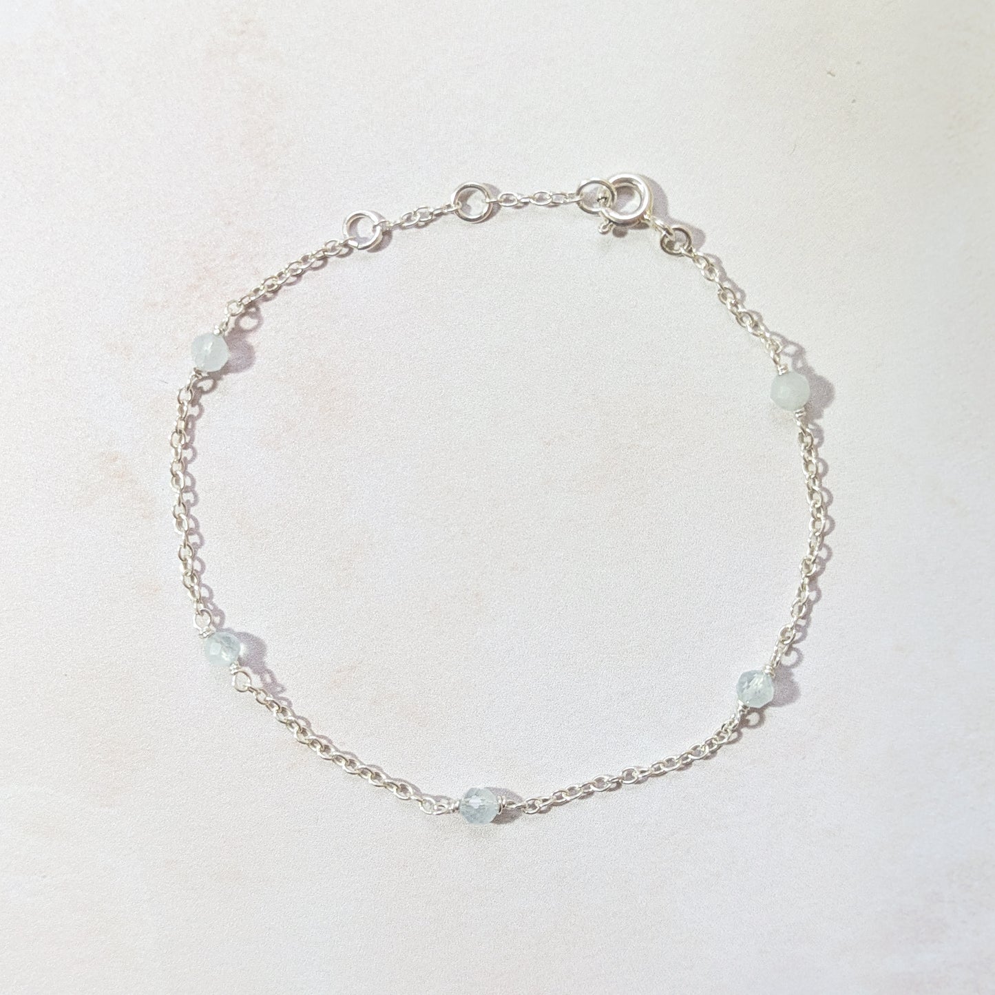 Silver bracelet with Aquamarine gemstone beads on a light background.