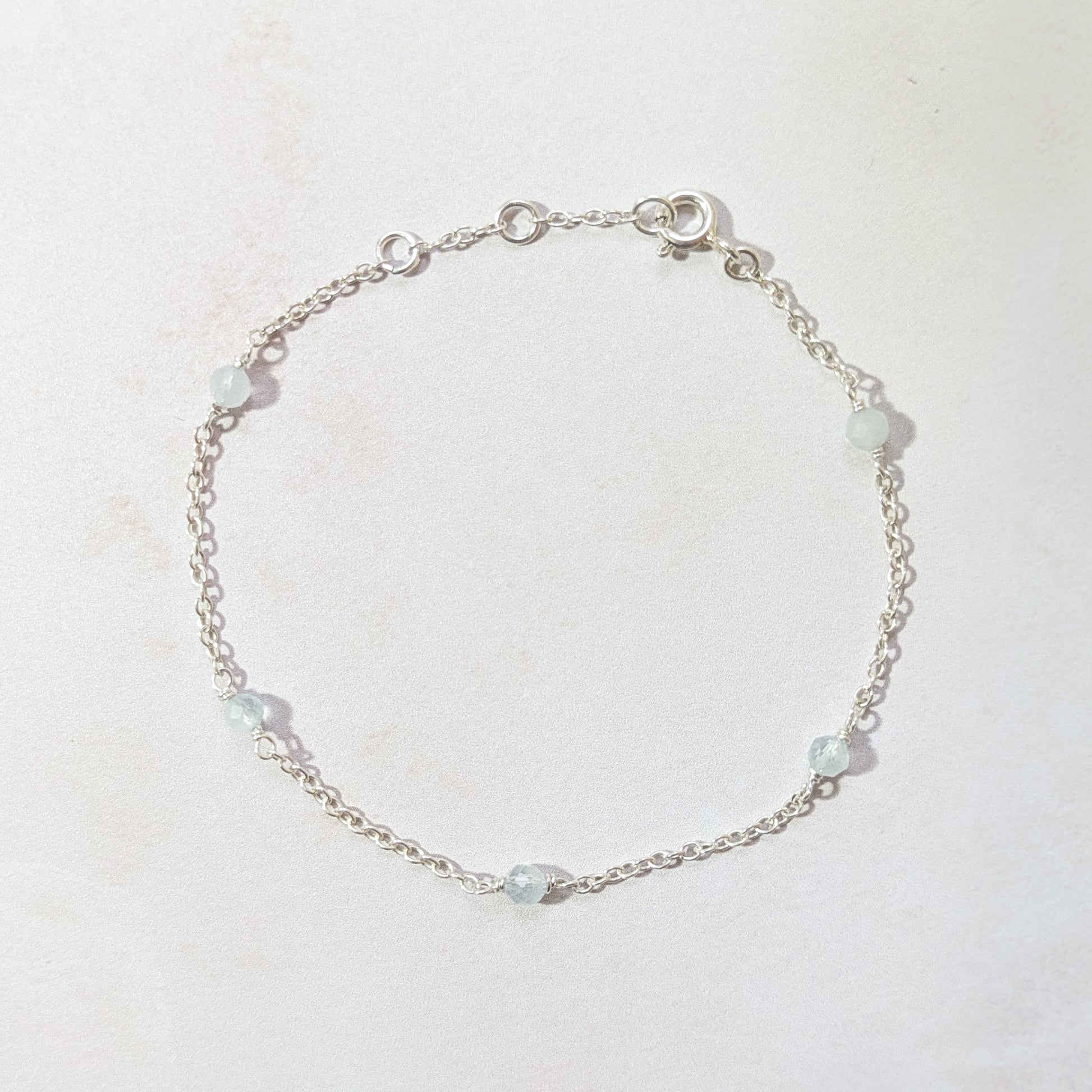 Silver bracelet with Aquamarine gemstone beads on a light background.