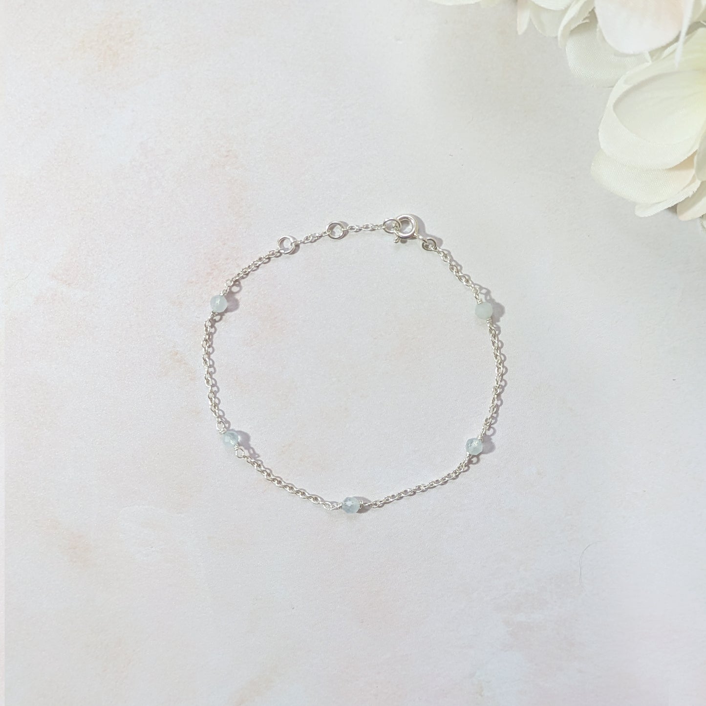 Silver station bracelet with Aquamarine gemstone beads on a light background.