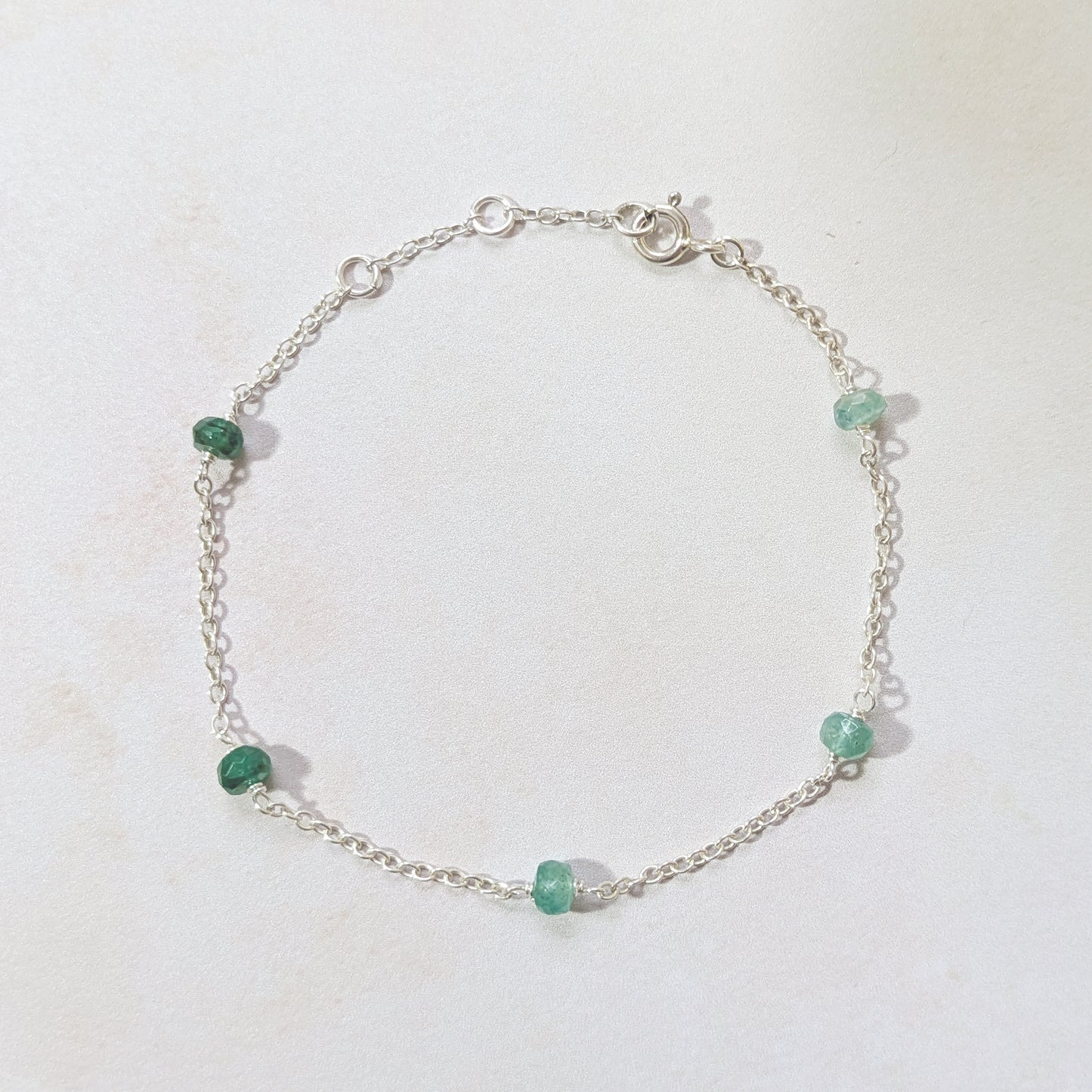 Silver bracelet with graduated Emerald gemstone beads on a white background.