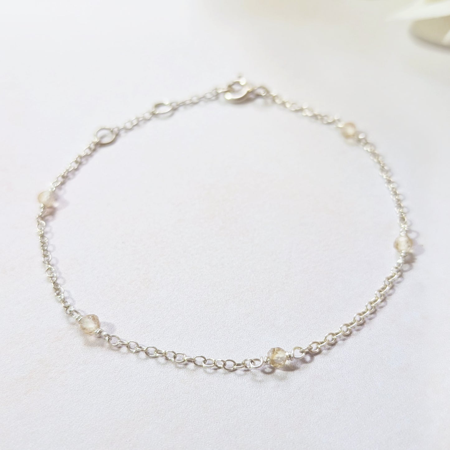 Delicate silver bracelet with small Citrine gemstone beads on a white background.