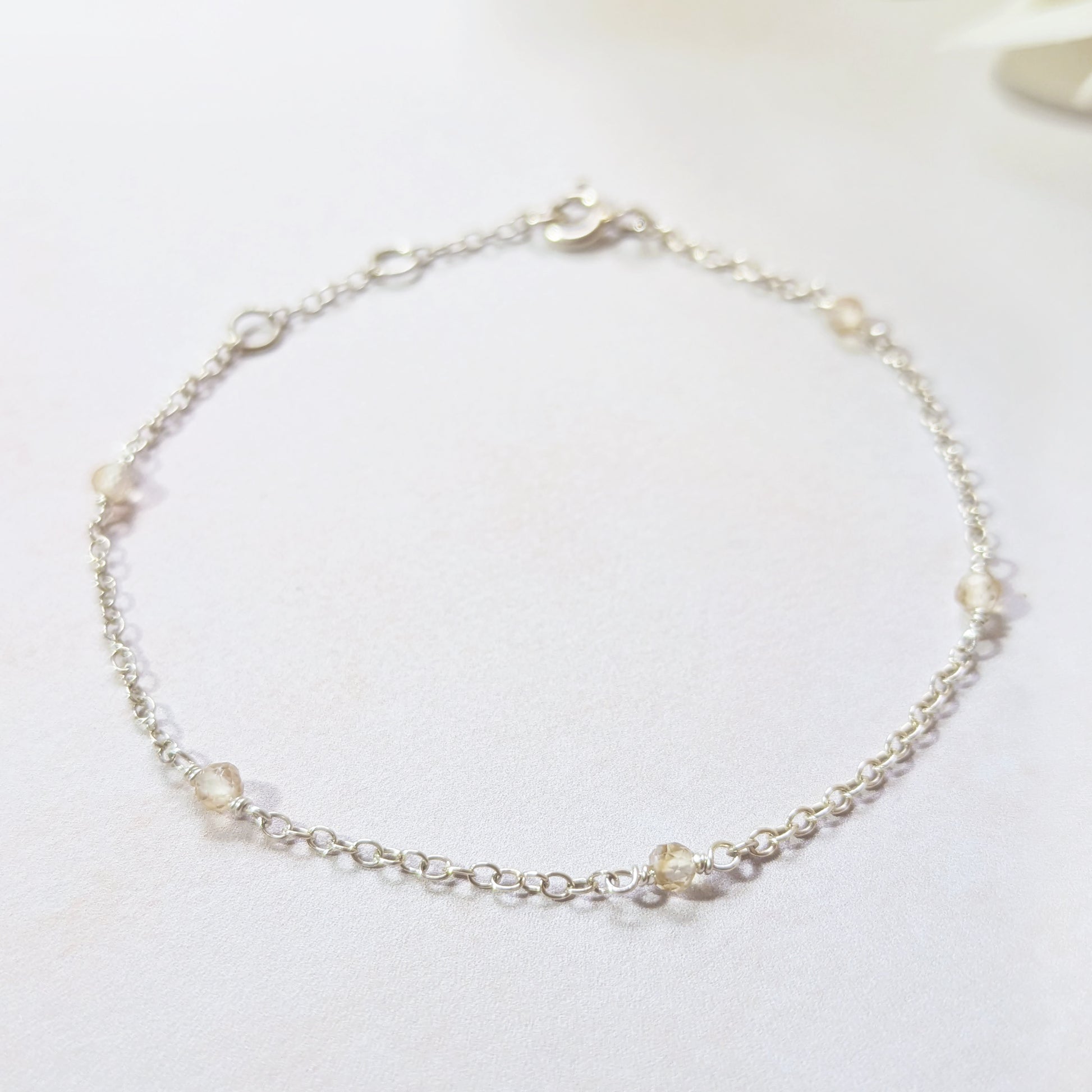 Delicate silver bracelet with small Citrine gemstone beads on a white background.