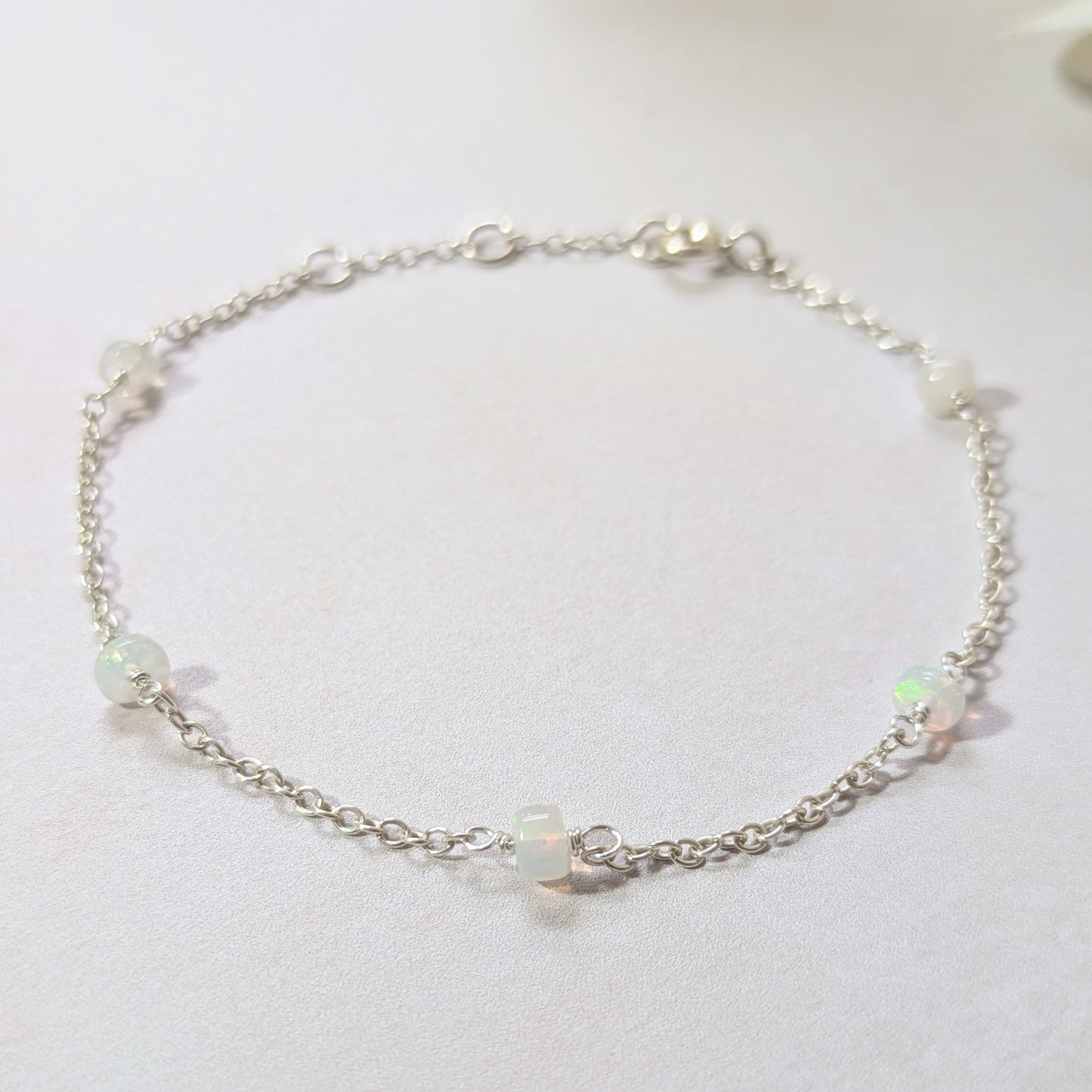 Silver station bracelet with Opal gemstone beads on a light background.