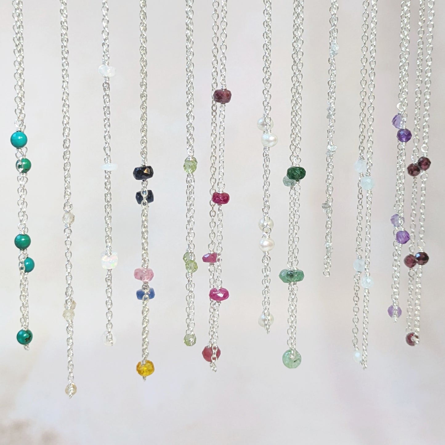 Colourful stationed gemstone bead necklaces on a white background.