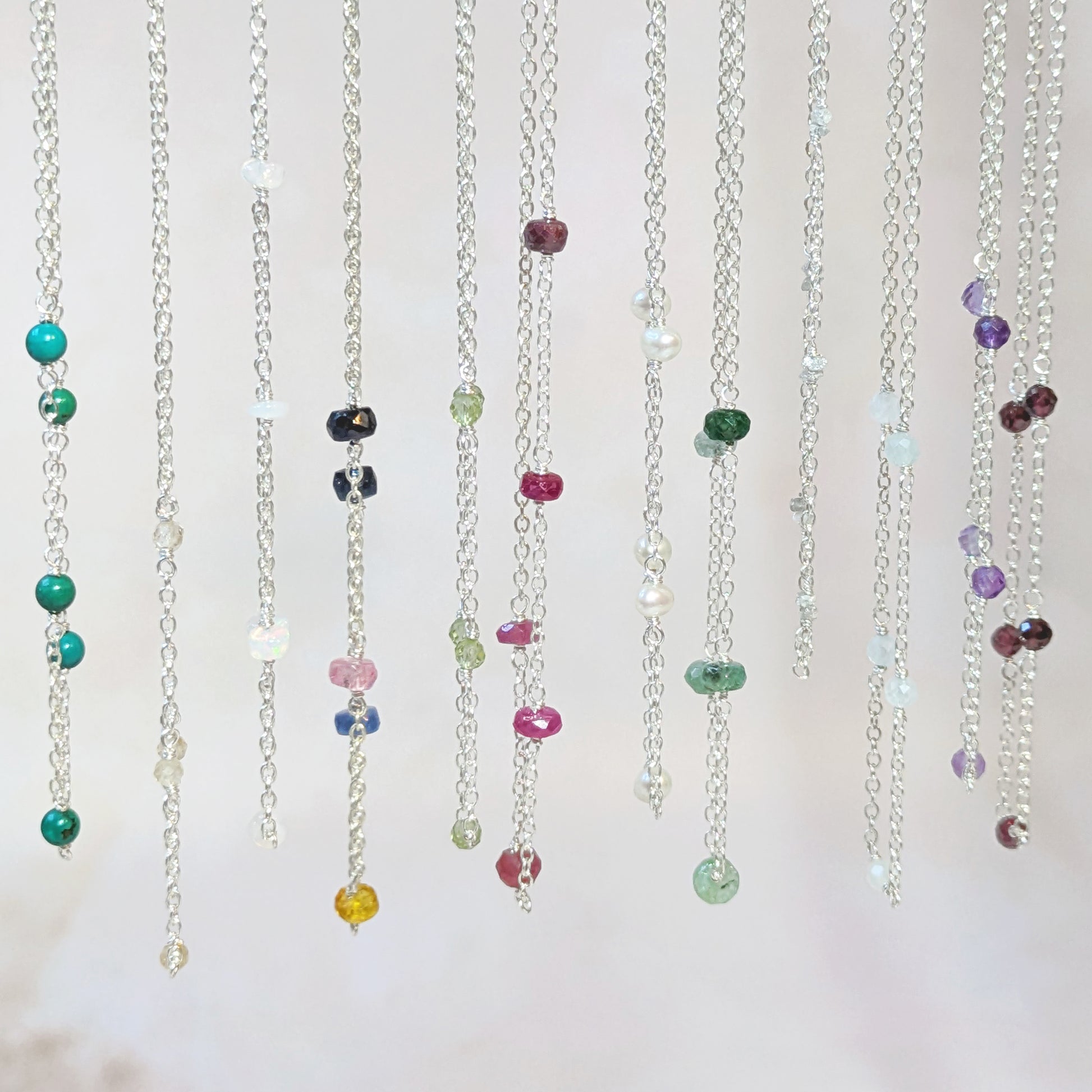 Colourful stationed gemstone bead necklaces on a white background.
