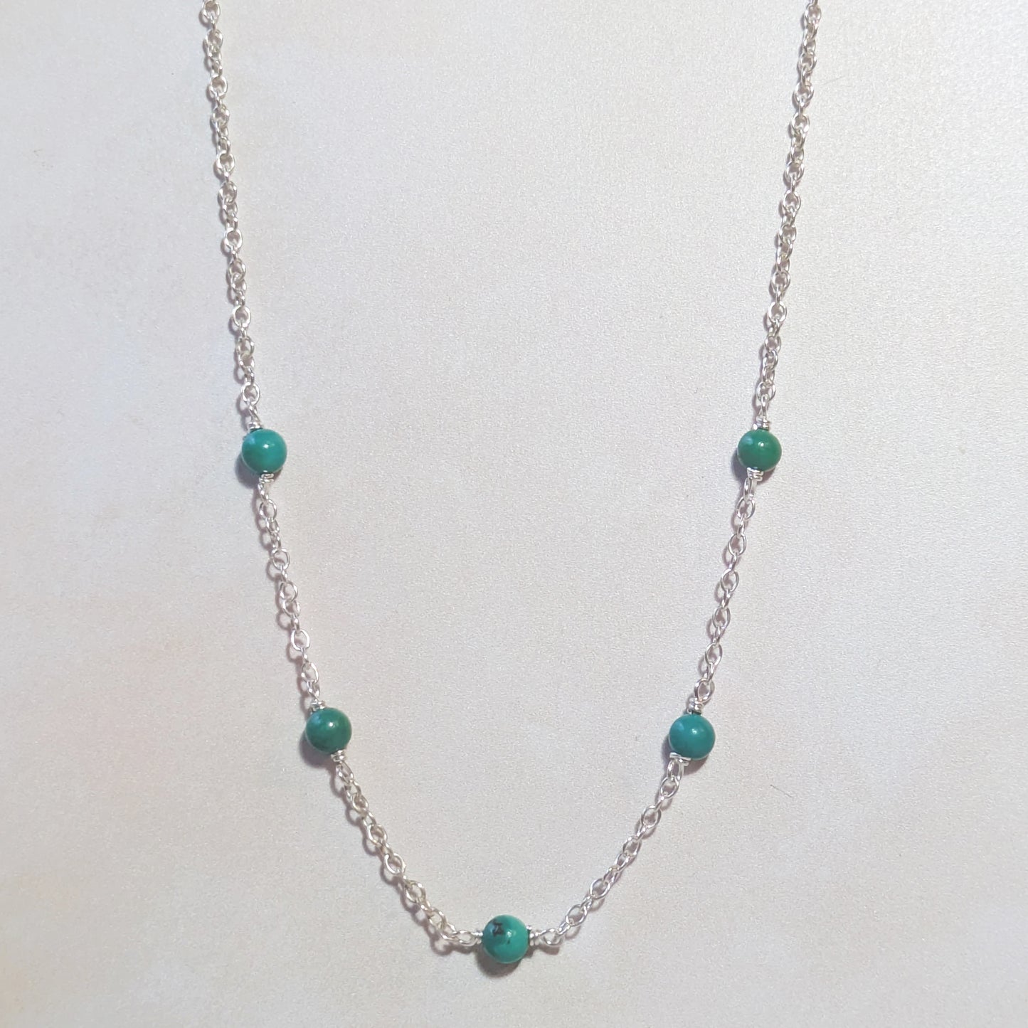 Silver necklace with Arizona Turquoise beads on a white background.