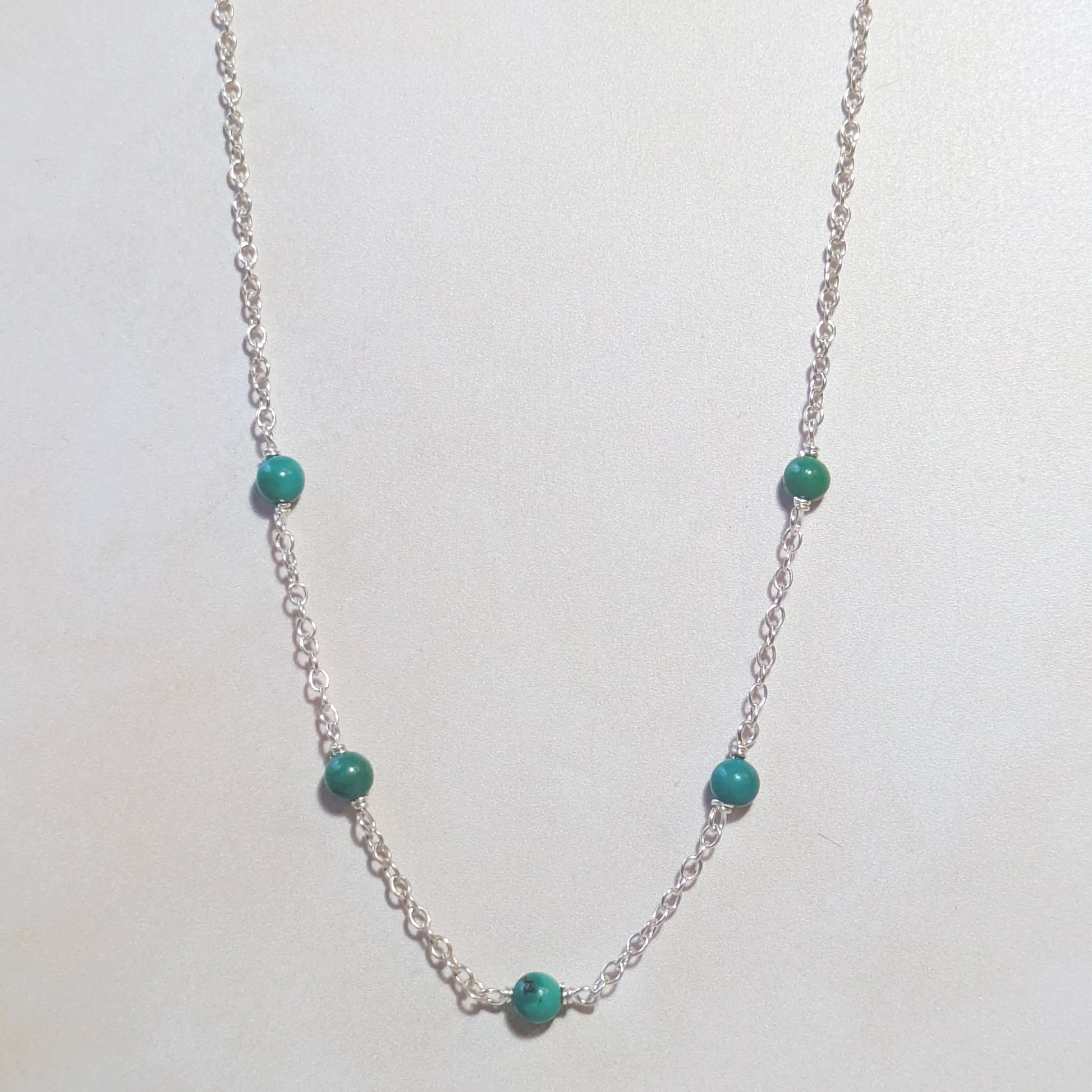 Silver necklace with Arizona Turquoise beads on a white background.