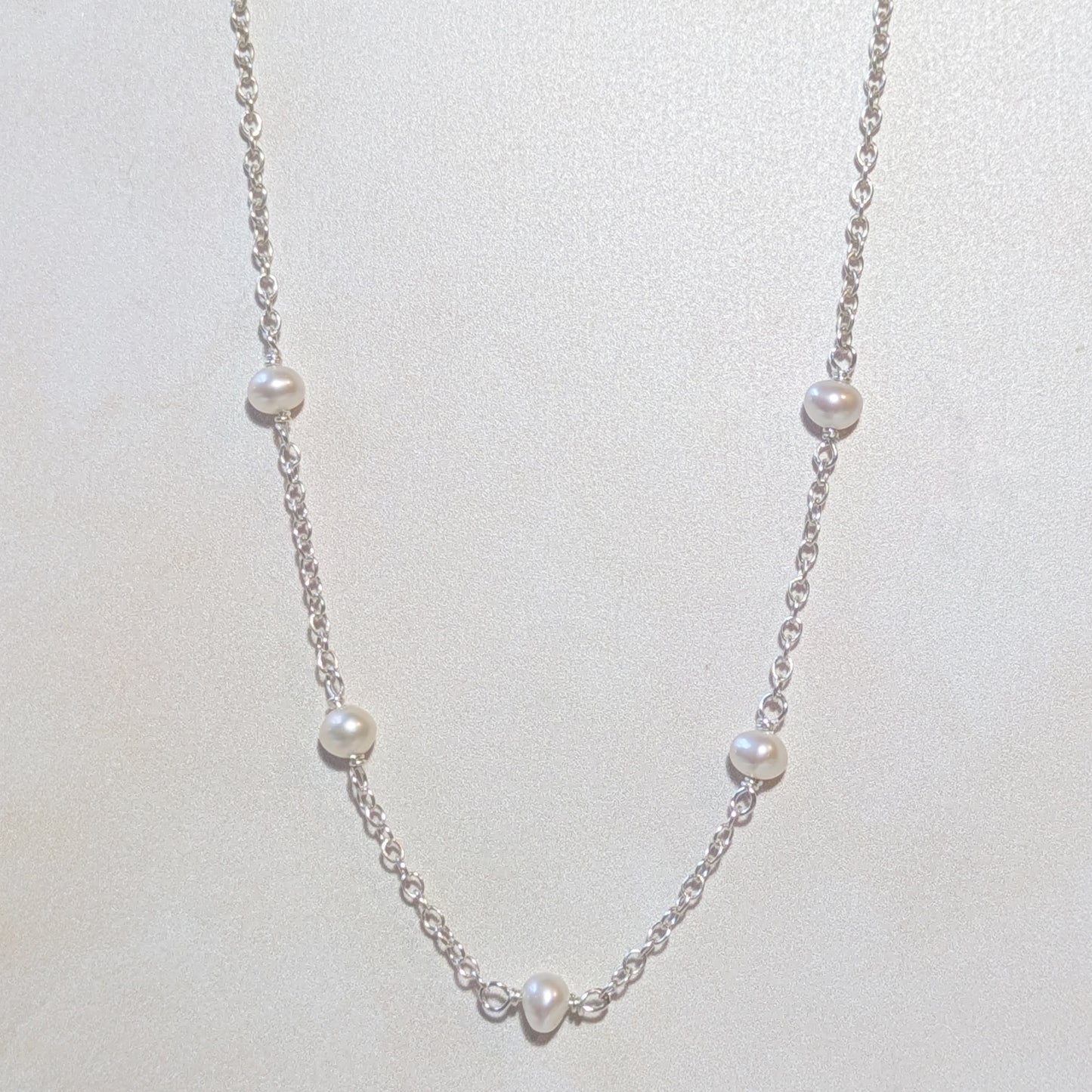 Pearl stationed necklace on a light neutral background.