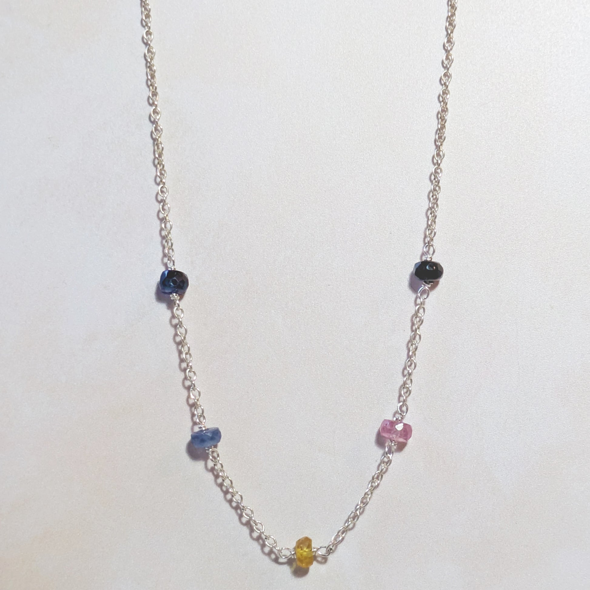 Necklace with multicoloured Sapphire beads on a white background.