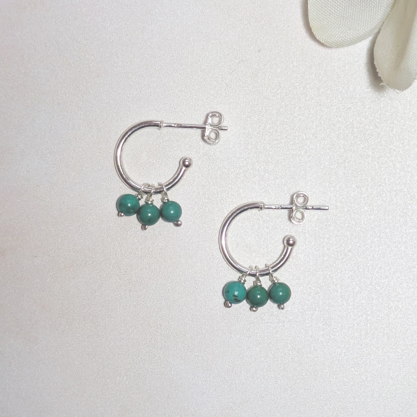Silver hoop earrings with natural Arizona Turquoise beads on a light gray background.