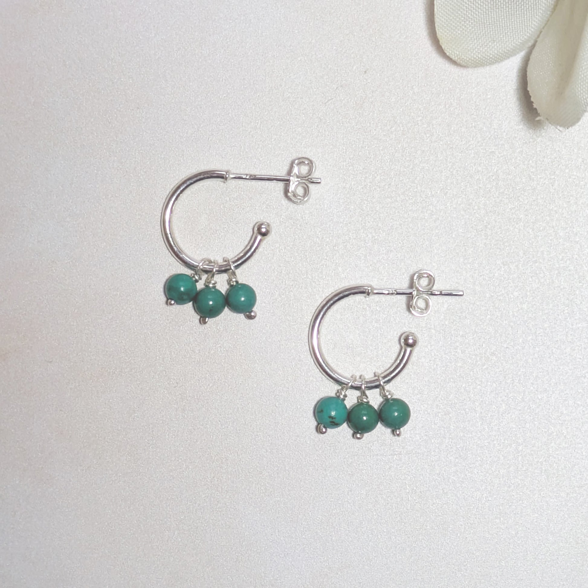Silver hoop earrings with natural Arizona Turquoise beads on a light gray background.