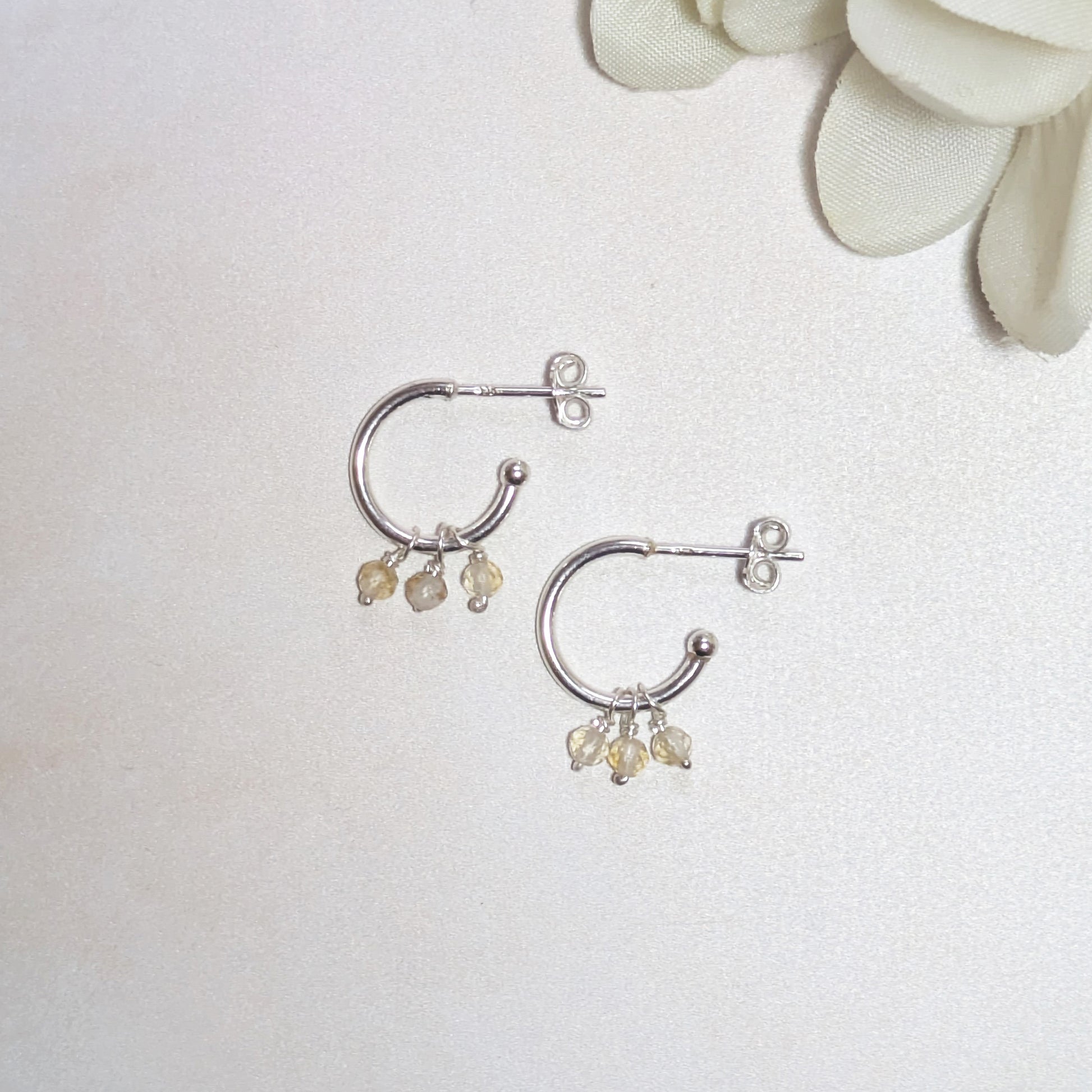 Silver hoop earrings with mini Citrine gemstones on a white background.