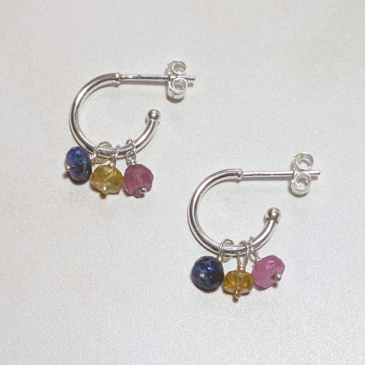 Silver hoop earrings with multicoloured Sapphire gemstones on a white background.