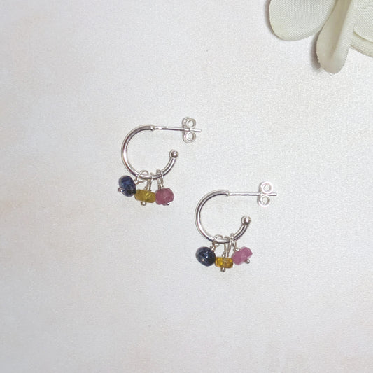 Silver hoop earrings with multicoloured Sapphire beads on a white background.