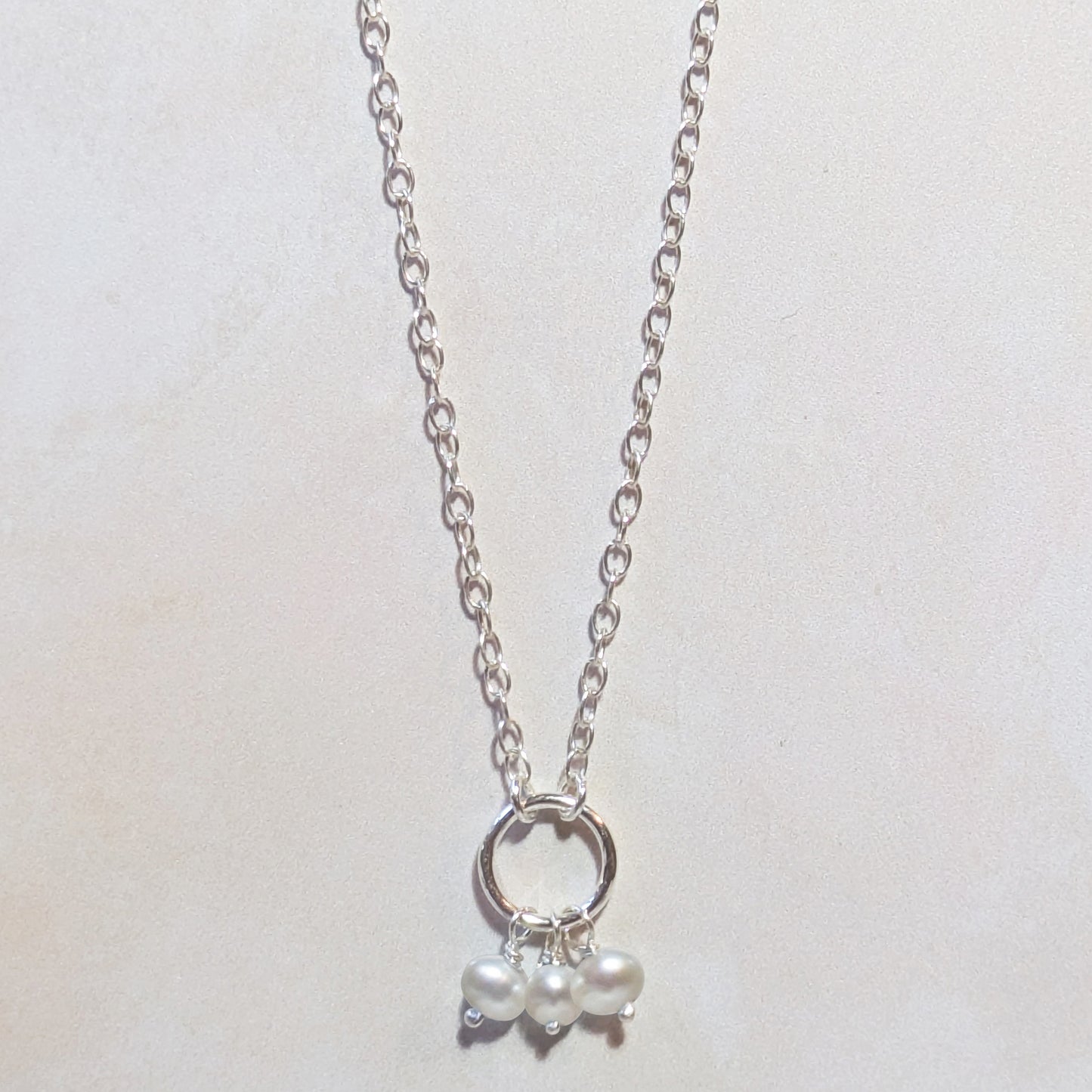 Silver necklace with a small Freshwater Pearl pendant on a light gray background.