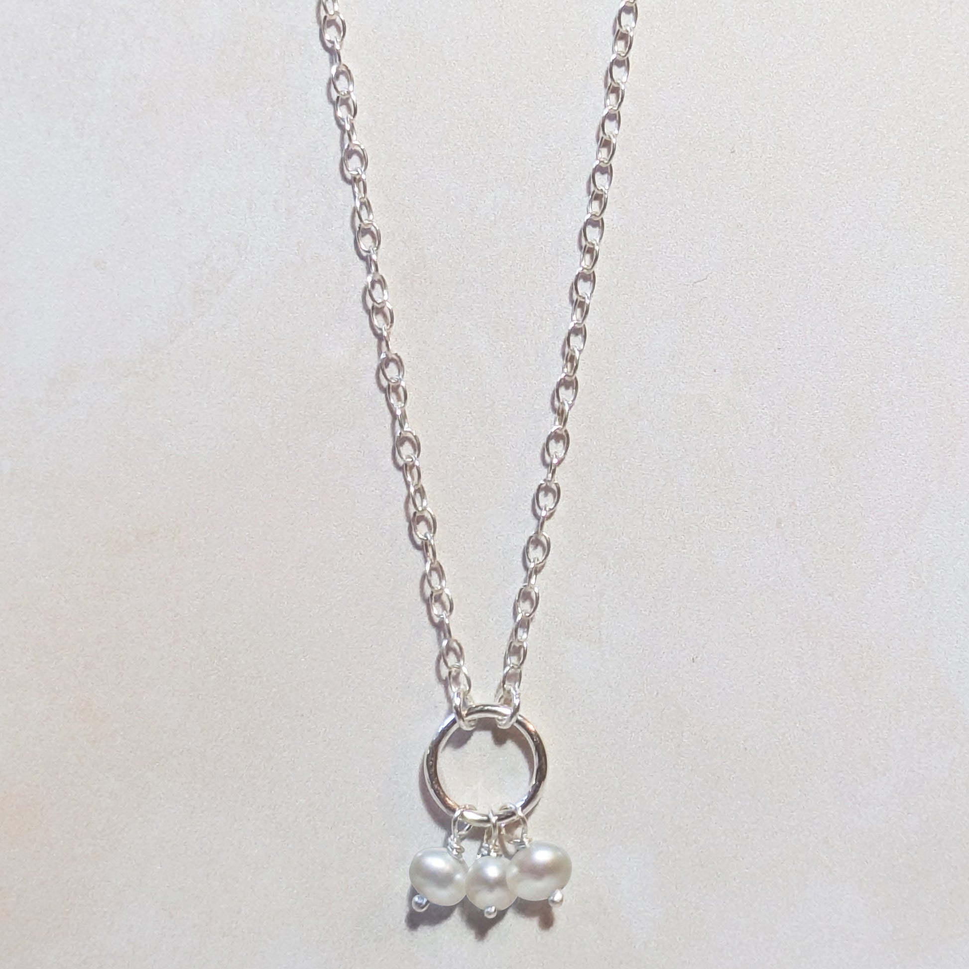 Silver necklace with a small Freshwater Pearl pendant on a light gray background.
