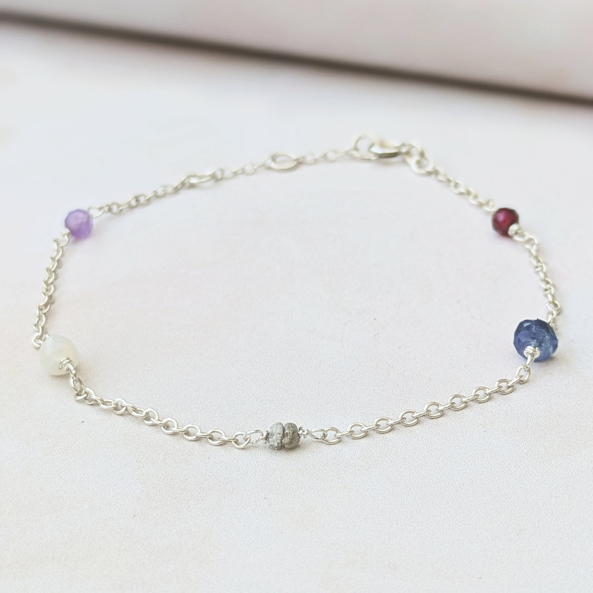 Close up macro view of our personalised family birthstone bracelet with Amethyst, Opal, Diamond, Sapphire and Garnet natural ethically sourced gemstone beads.