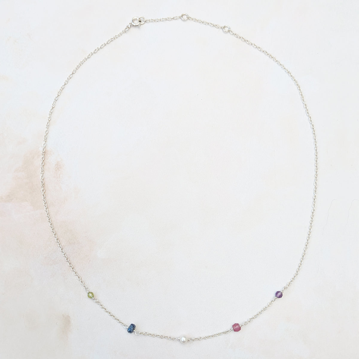 Full view of our adjustable personalised sterling silver family birthstone necklace  featuring natural ethically sourced gemstone beads shown on a neutral background.