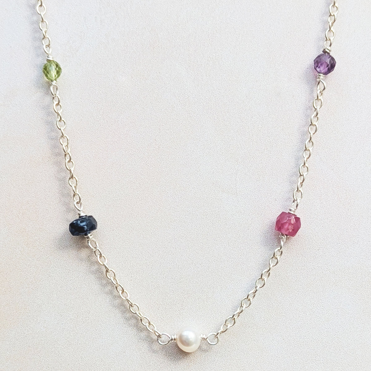 Close up macro view of our personalised sterling silver family birthstone necklace  featuring natural ethically sourced gemstone beads shown on a white background.