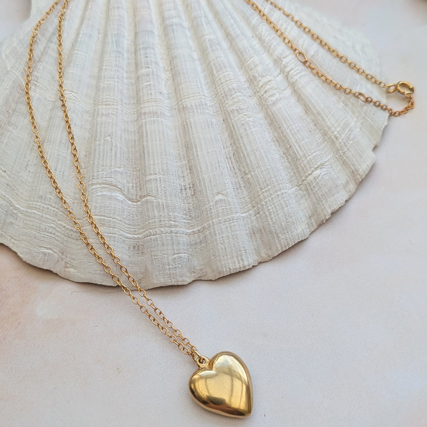 18ct Gold Vermeil heart necklace draped over a shell.
