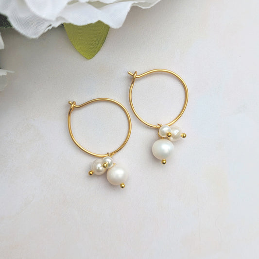 Pearl Hoop Earrings on a white background with flowers.