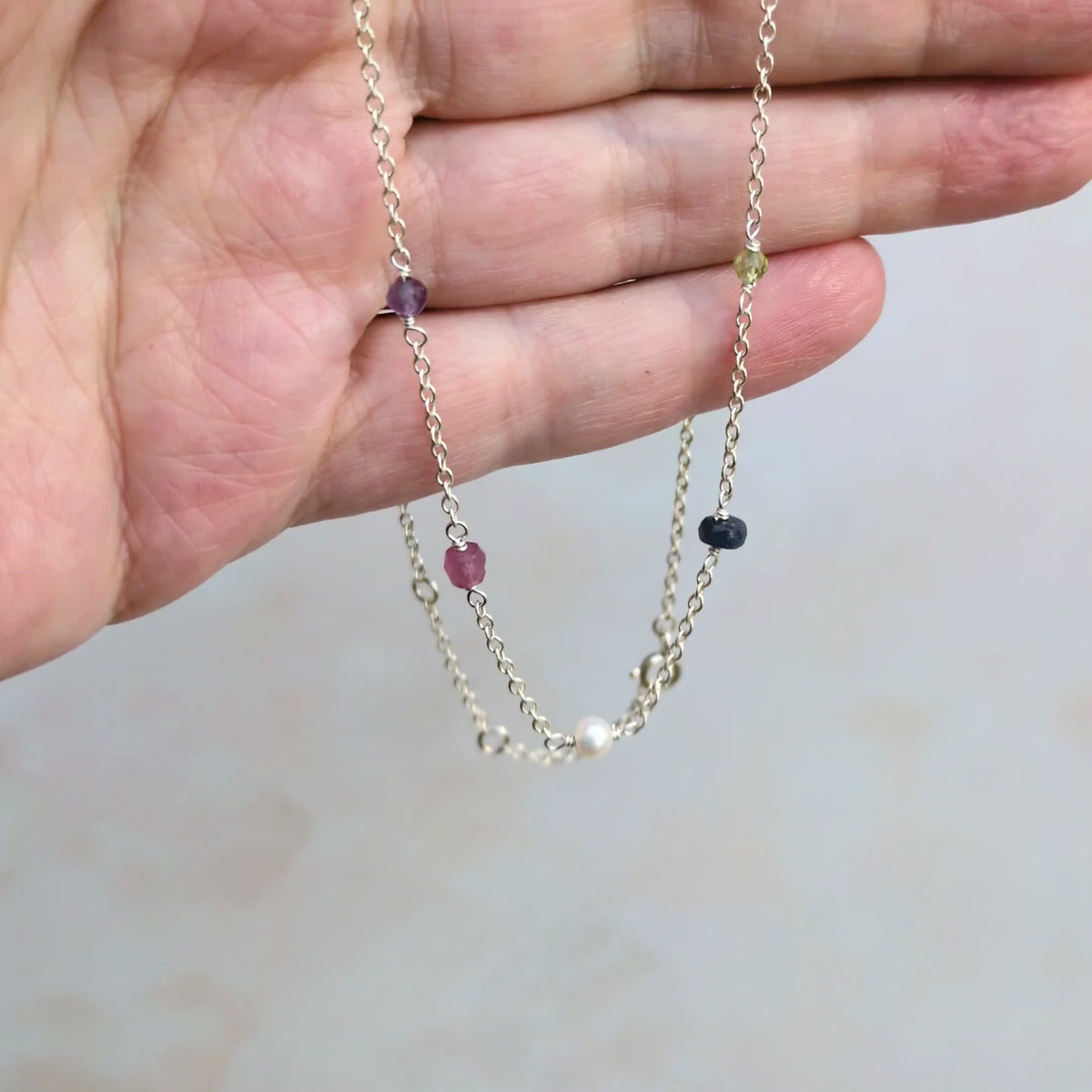 Video of personalised sterling silver family birthstone necklace  featuring natural ethically sourced gemstone beads shown in the hand.