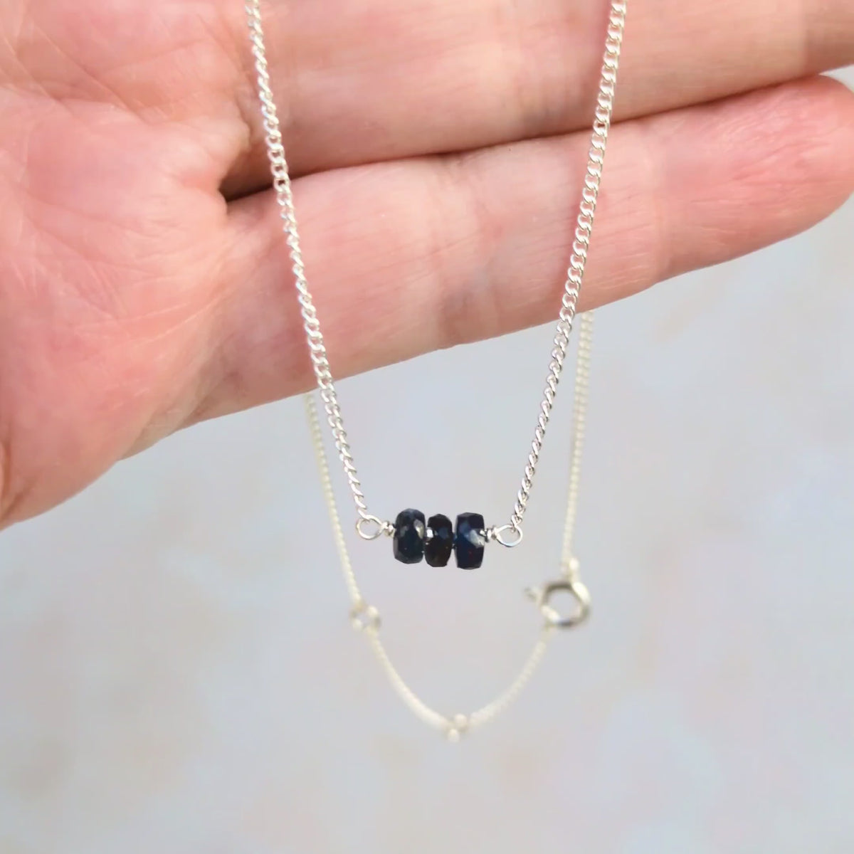 Video showing a sapphire bar necklace being held in a real persons hand.