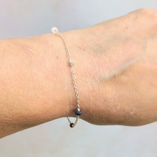Video showing a woman wearing the family birthstone bracelet against a pale grey background.