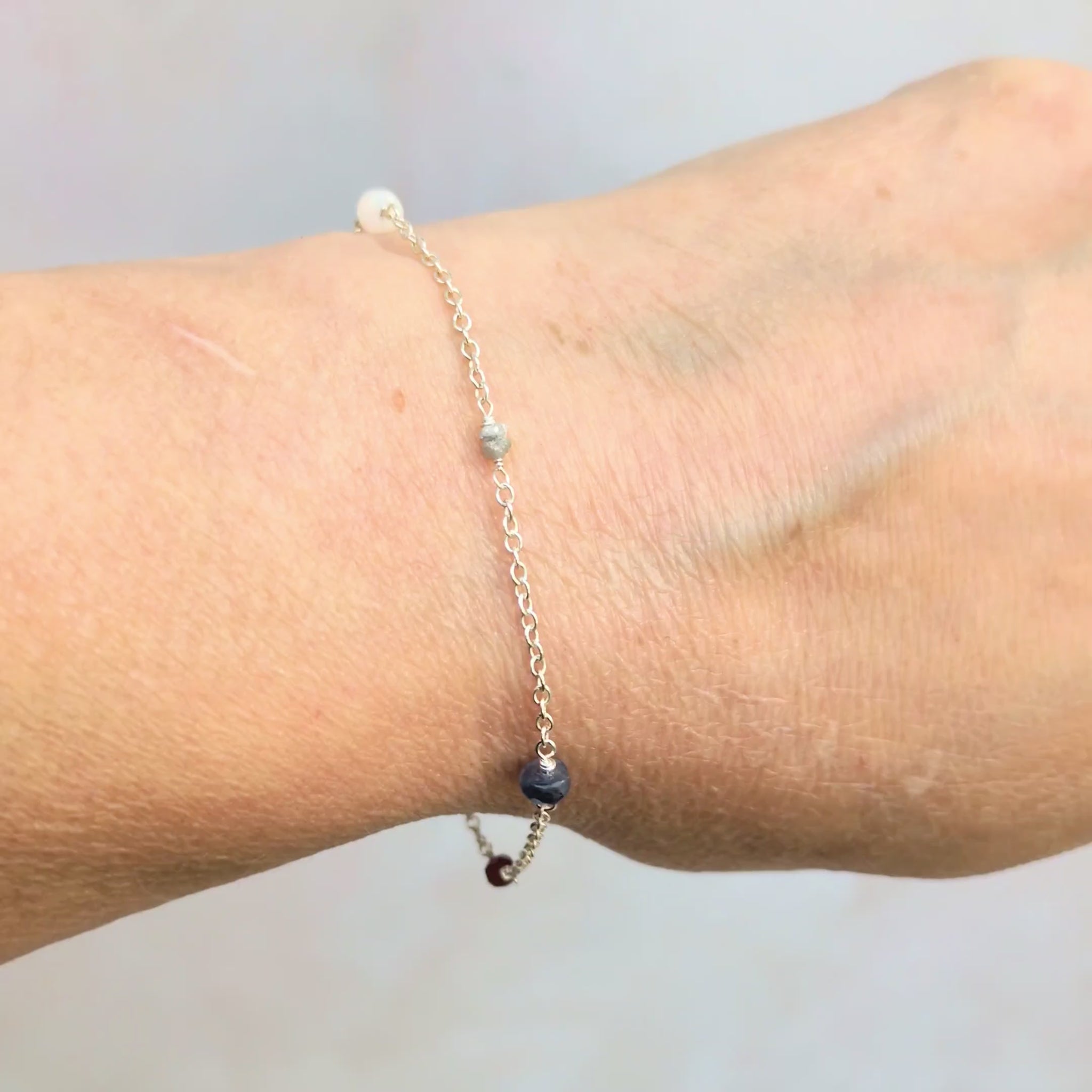 Video showing a woman wearing the family birthstone bracelet against a pale grey background.